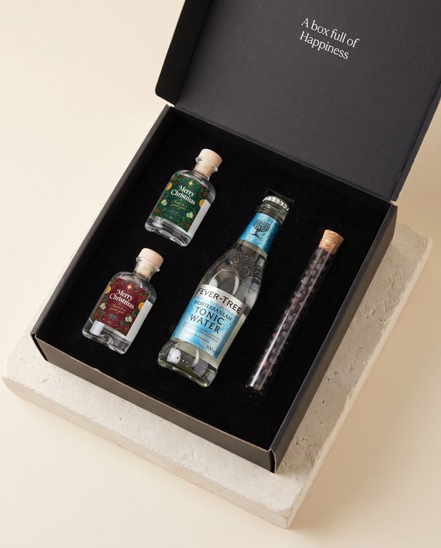 Premium box met eigen kerstetiket: twee miniflesjes gin, tonic en kruidentube in de zwarte doos