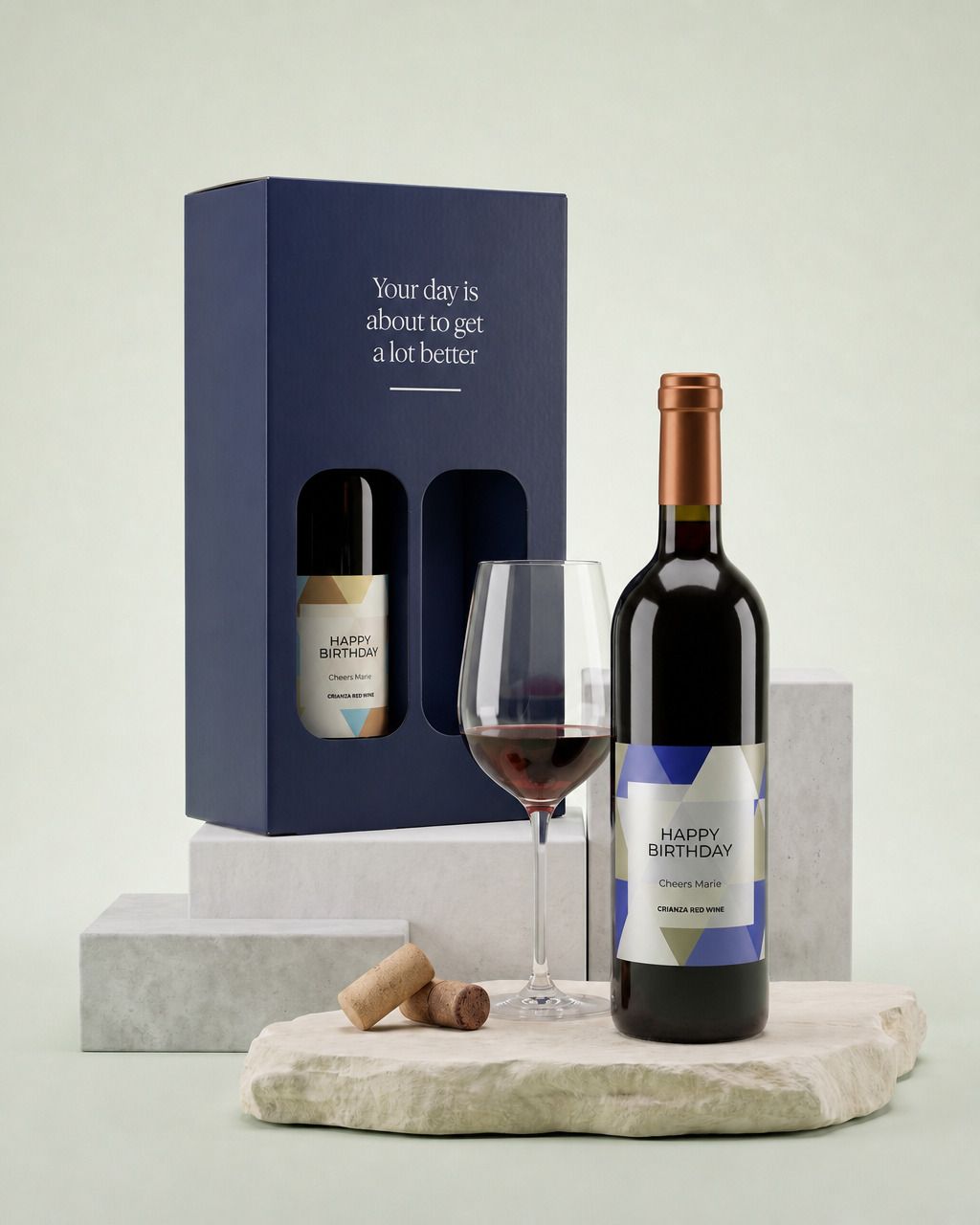 Wijnpakket met twee flessen met een gepersonaliseerd verjaardagsetiket, met een gevuld wijnglas ernaast